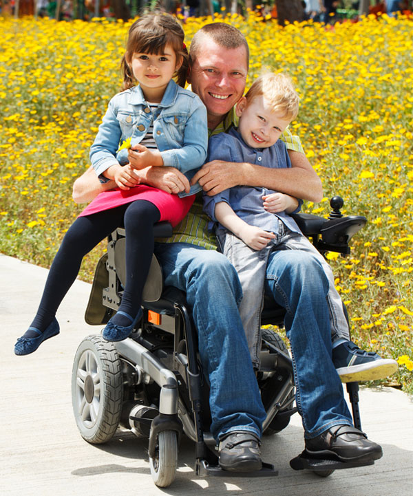 Man in wheelchair holding his son and daughter